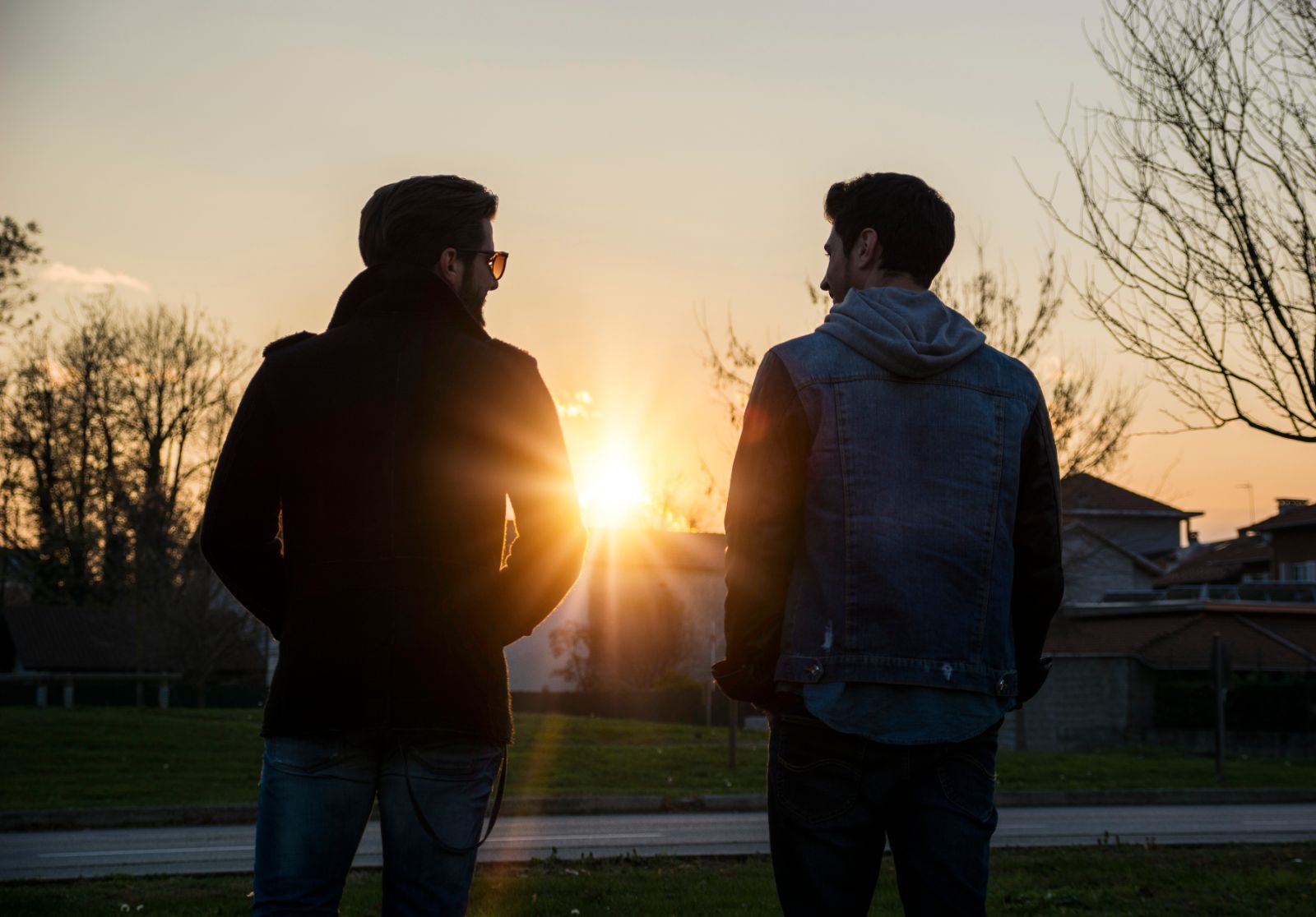 Two men standing outdoors at sunset facing each other in conversation