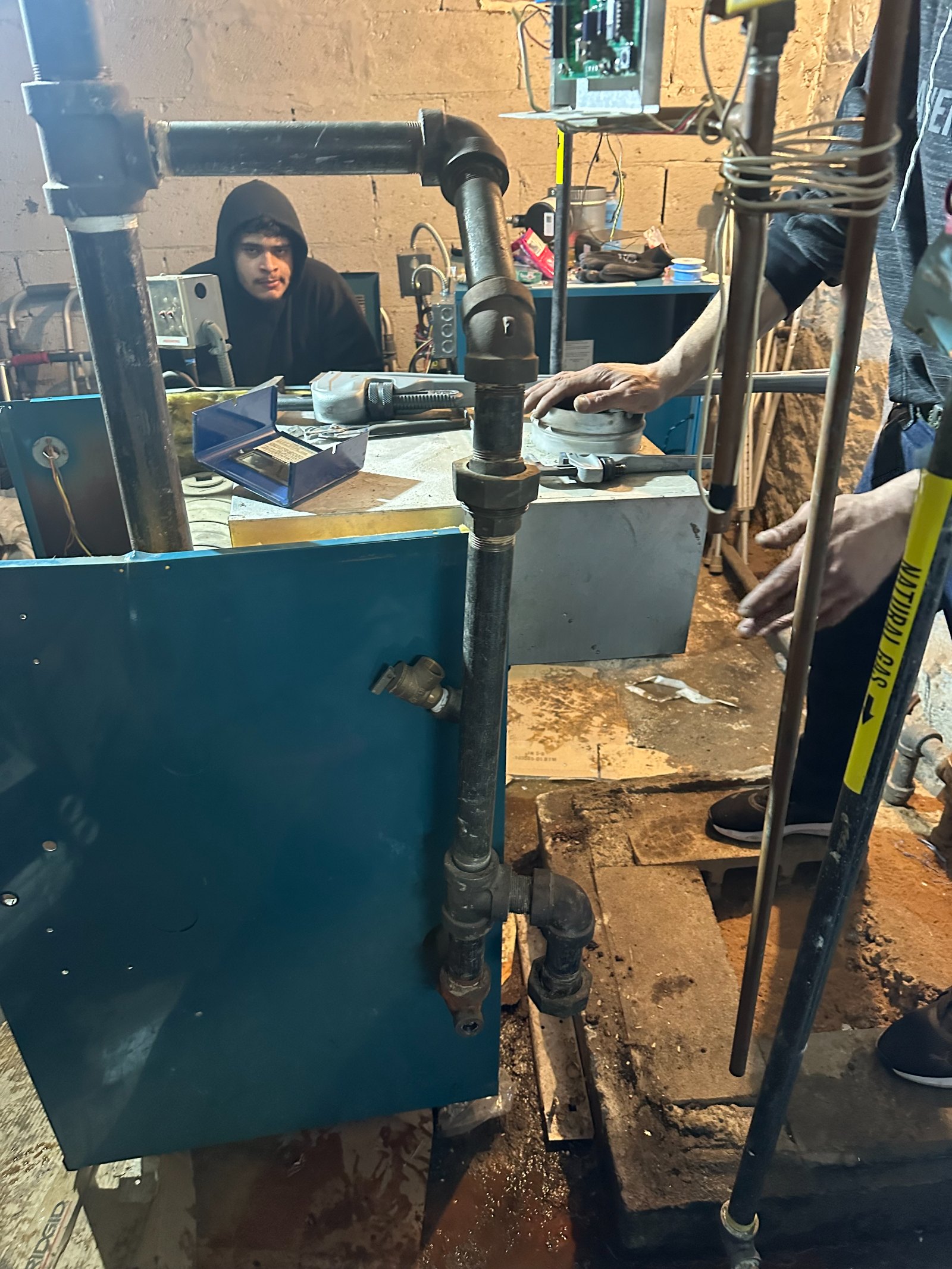 Industrial workshop with person at workbench operating machinery with metal pipes and blue equipment